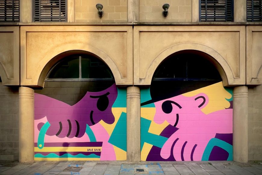 A painting on a wall of two children playing in the sand